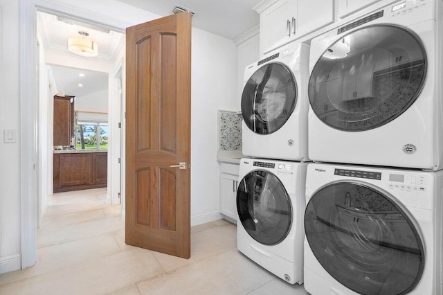 laundry area with light tile floors, cabinets, crown molding, and stacked washer / drying machine