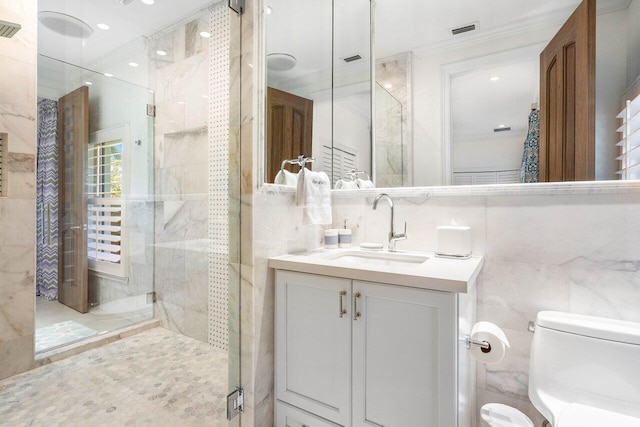 bathroom featuring toilet, oversized vanity, a shower with door, ornamental molding, and tile walls