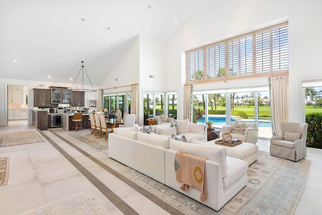 living room featuring light tile floors, high vaulted ceiling, and an inviting chandelier