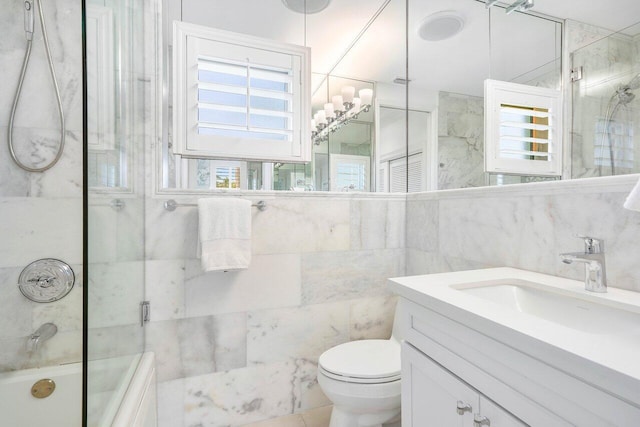 full bathroom with toilet, oversized vanity, tile walls, combined bath / shower with glass door, and tile flooring