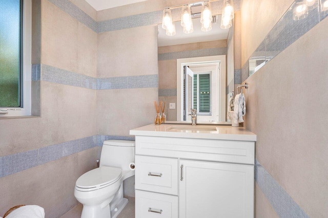 bathroom with large vanity, toilet, and tile walls