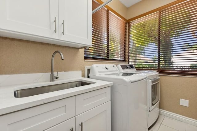 laundry room featuring sink, washer and dryer, light tile patterned flooring, and cabinets