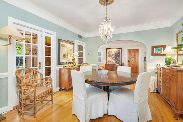 dining space featuring light wood-type flooring, a notable chandelier, and crown molding