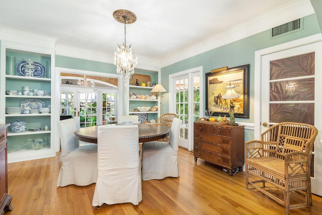 dining area with a wealth of natural light, built in shelves, and light hardwood / wood-style flooring