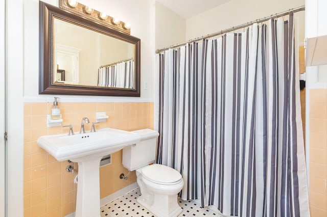 bathroom with toilet, a shower with shower curtain, tile patterned flooring, and tile walls