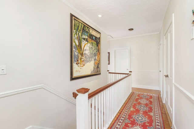 hall featuring light wood-type flooring, a textured ceiling, and crown molding