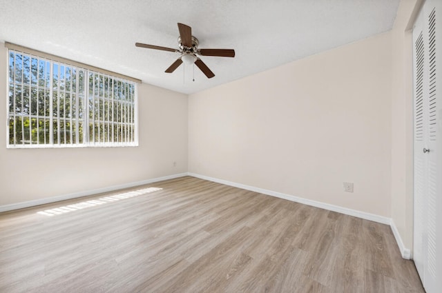 empty room with light hardwood / wood-style floors, ceiling fan, and a textured ceiling