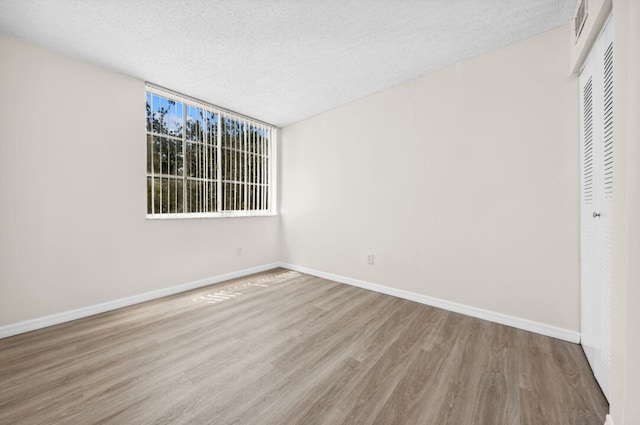 spare room with a textured ceiling and wood-type flooring