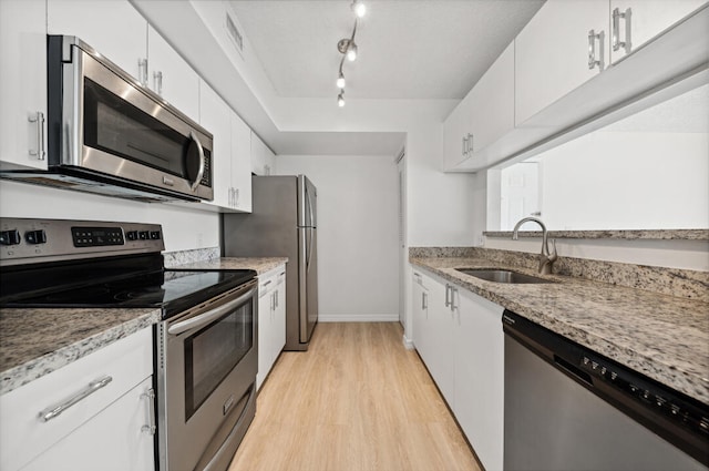 kitchen featuring white cabinetry, appliances with stainless steel finishes, track lighting, sink, and light wood-type flooring