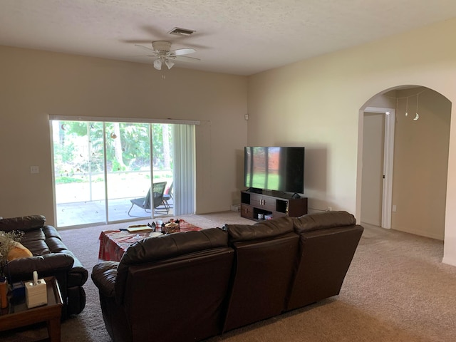 living room featuring light carpet, ceiling fan, and a textured ceiling