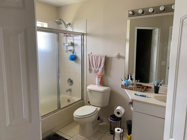 full bathroom featuring tile floors, enclosed tub / shower combo, toilet, and vanity