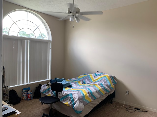 carpeted bedroom with ceiling fan and a textured ceiling