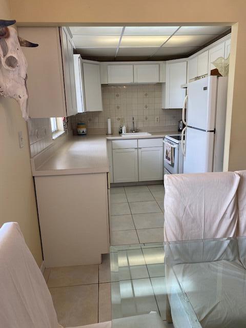 kitchen with light tile floors, white refrigerator, tasteful backsplash, range, and sink