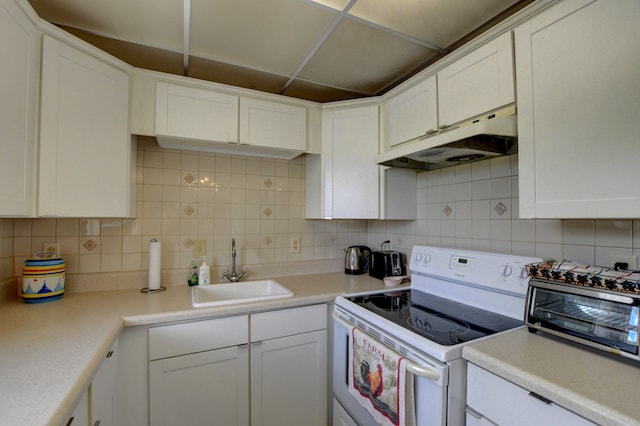 kitchen featuring tasteful backsplash, white cabinetry, and electric range