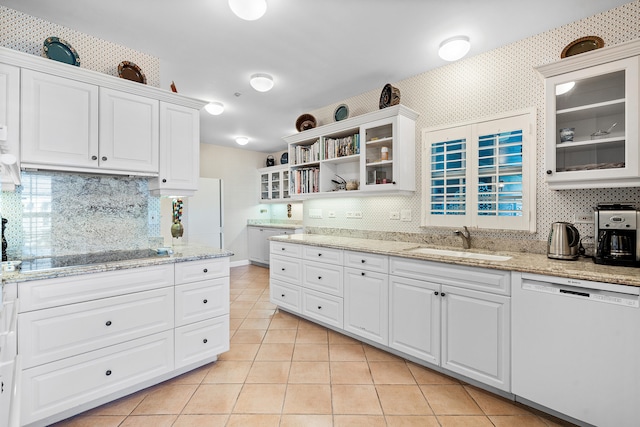 kitchen featuring tasteful backsplash, white cabinetry, white dishwasher, sink, and light tile floors