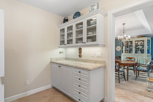 kitchen featuring an inviting chandelier, hanging light fixtures, tasteful backsplash, white cabinetry, and light tile floors