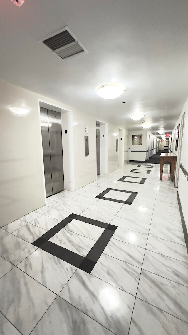 hallway with light tile floors and elevator