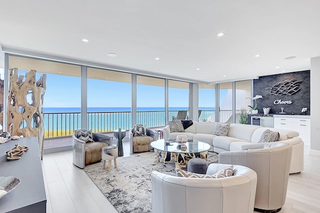 living room with a water view, light hardwood / wood-style flooring, and floor to ceiling windows