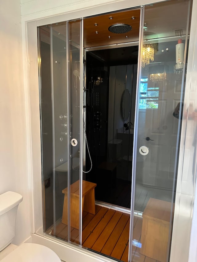 bathroom with a chandelier, toilet, and a shower with shower door