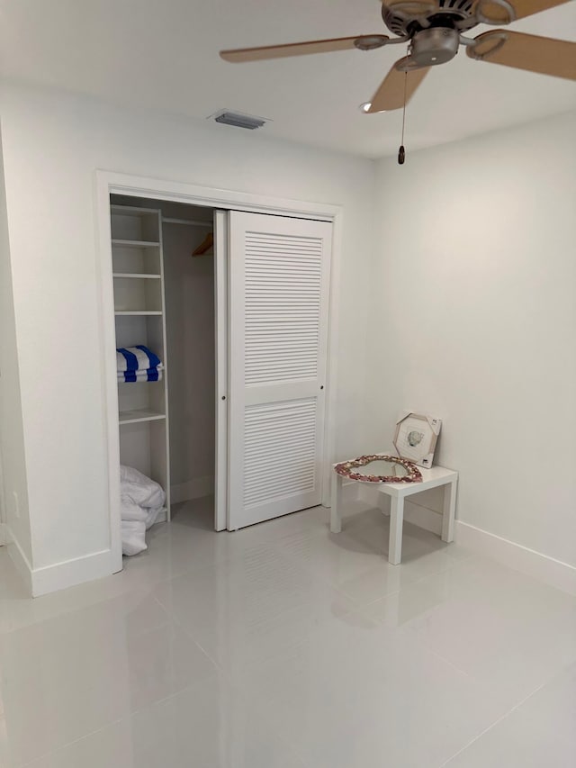 unfurnished bedroom with light tile flooring, a closet, and ceiling fan