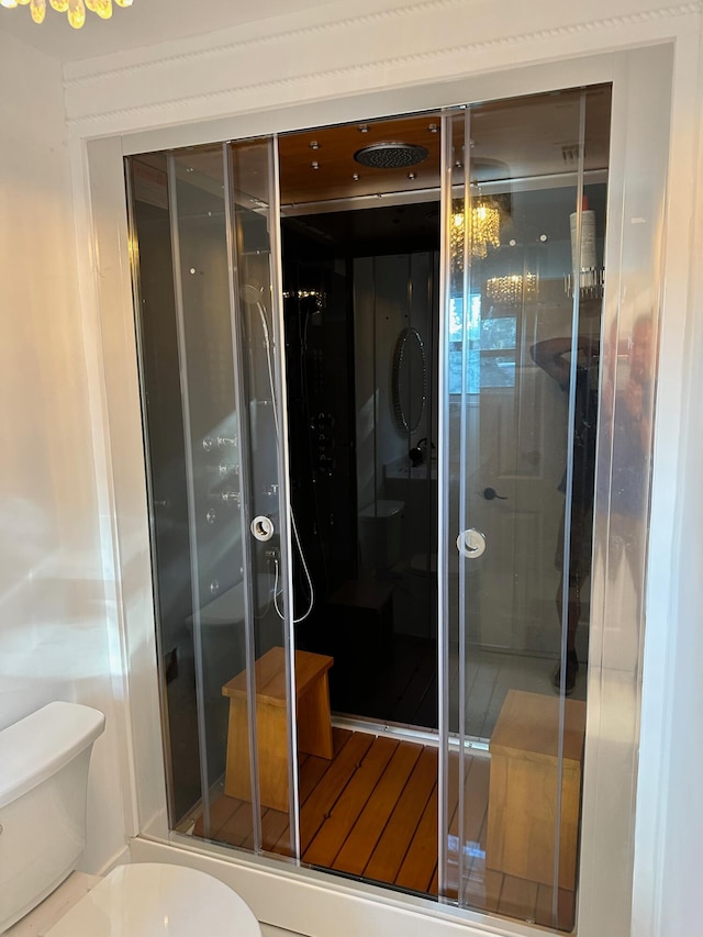 bathroom featuring toilet and a shower with door