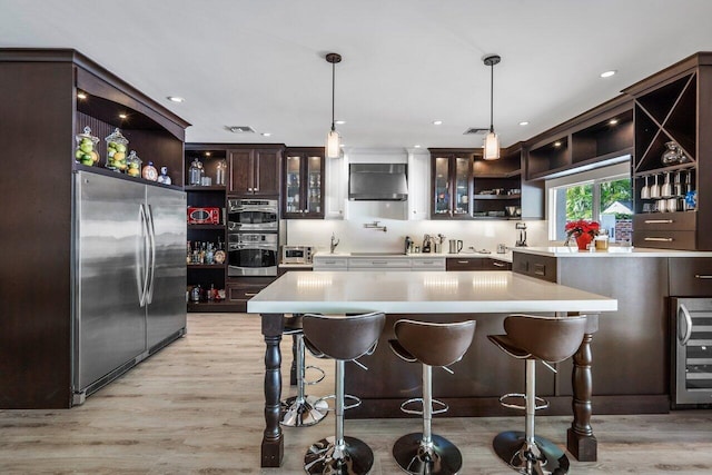 kitchen featuring appliances with stainless steel finishes, light hardwood / wood-style flooring, and pendant lighting