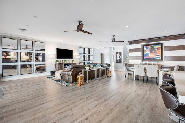 living room featuring plenty of natural light, light hardwood / wood-style floors, ceiling fan, and crown molding