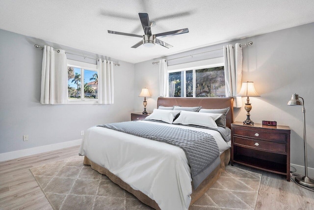 bedroom with ceiling fan, light hardwood / wood-style flooring, and a textured ceiling