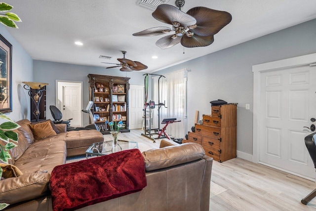 living room featuring a textured ceiling, ceiling fan, and light wood-type flooring