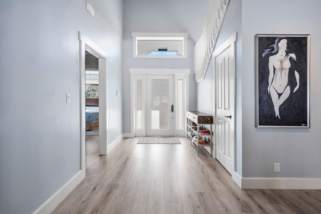 entryway with light wood-type flooring and a high ceiling