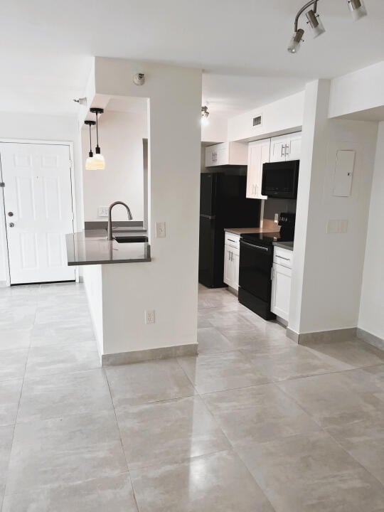 kitchen featuring light tile floors, white cabinetry, and black appliances