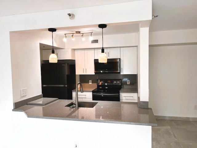 kitchen featuring decorative light fixtures, range with electric stovetop, kitchen peninsula, and black fridge