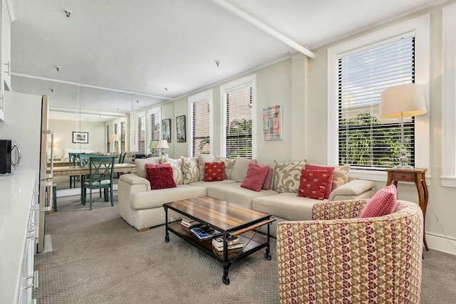 living room with plenty of natural light, ornamental molding, and light colored carpet