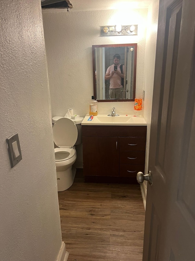 bathroom with toilet, vanity, and hardwood / wood-style flooring