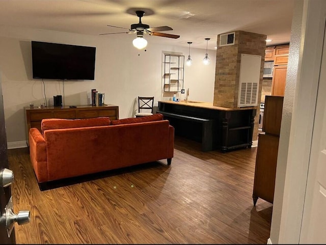 living room featuring ceiling fan, brick wall, sink, and dark wood-type flooring