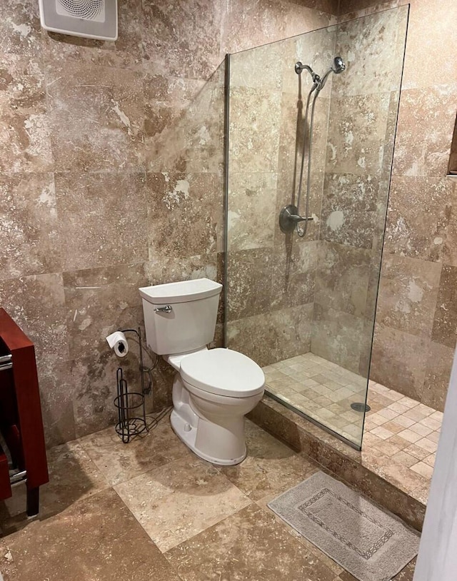 bathroom featuring tile flooring, tiled shower, and toilet