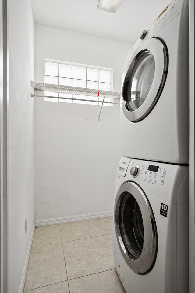 laundry room with plenty of natural light, stacked washer and dryer, and light tile floors