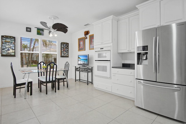 kitchen with white cabinets, white double oven, stainless steel fridge with ice dispenser, and light tile floors