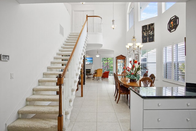 interior space featuring a notable chandelier, a towering ceiling, and light tile floors