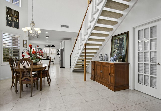 dining area featuring a high ceiling, light tile floors, and an inviting chandelier