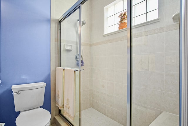 bathroom with a shower with door and toilet