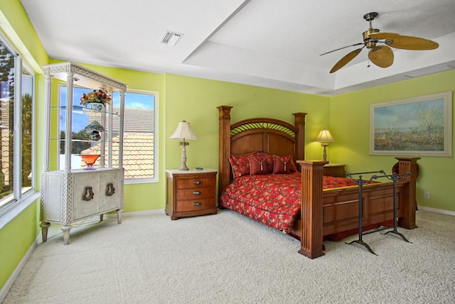 carpeted bedroom with ceiling fan and a tray ceiling