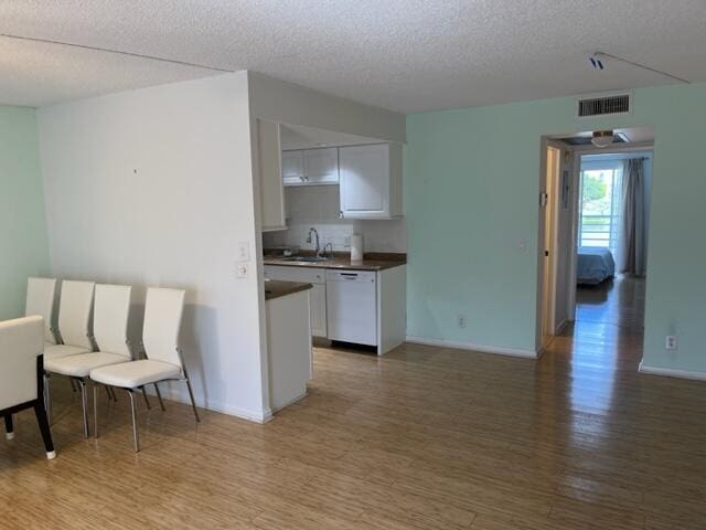 kitchen featuring sink, white cabinets, white dishwasher, and hardwood / wood-style flooring