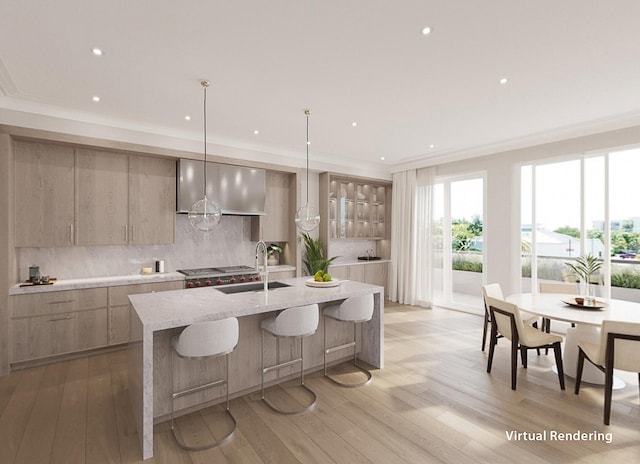 kitchen featuring light wood-type flooring, a kitchen island with sink, decorative light fixtures, sink, and decorative backsplash