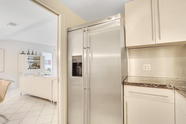 kitchen with light tile floors, white cabinets, and stainless steel fridge