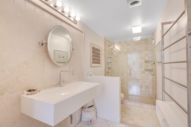 bathroom with tile walls, tile floors, sink, toilet, and a shower with shower door