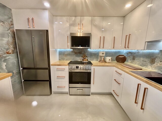 kitchen with wood counters, white cabinetry, and appliances with stainless steel finishes