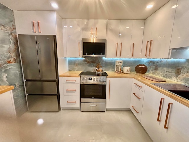 kitchen with wooden counters, white cabinetry, stainless steel appliances, and tasteful backsplash