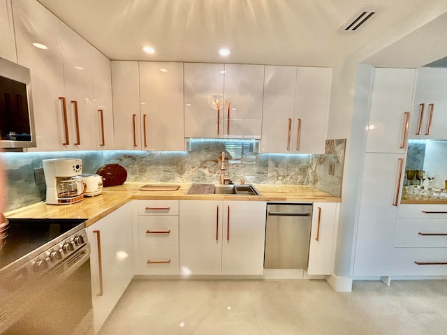 kitchen featuring decorative backsplash, white cabinetry, sink, and appliances with stainless steel finishes