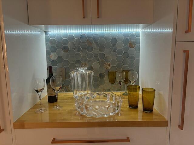 interior space with decorative backsplash, white cabinetry, dishwasher, and sink